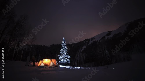 A night sky timelapse of winter camping with a tent in the snow under the stars. 
