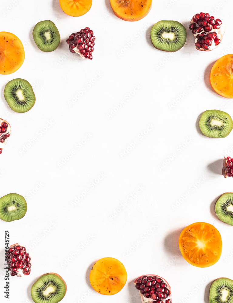 Seasonal healthy natural fruit frame with persimmon, kiwi, pomegranate slices Seasonal healthy natural fruit frame with persimmon, kiwi, pomegranate slices