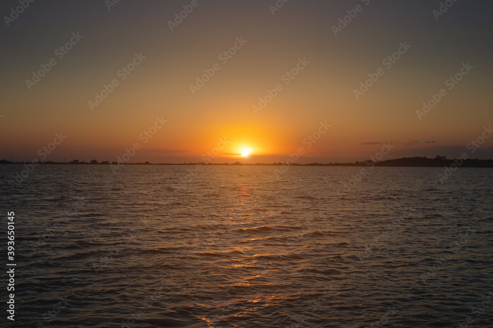 A colorful sunset over a bay or lake with a calm water surface. Late evening. Low key
