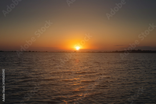 A colorful sunset over a bay or lake with a calm water surface. Late evening. Low key