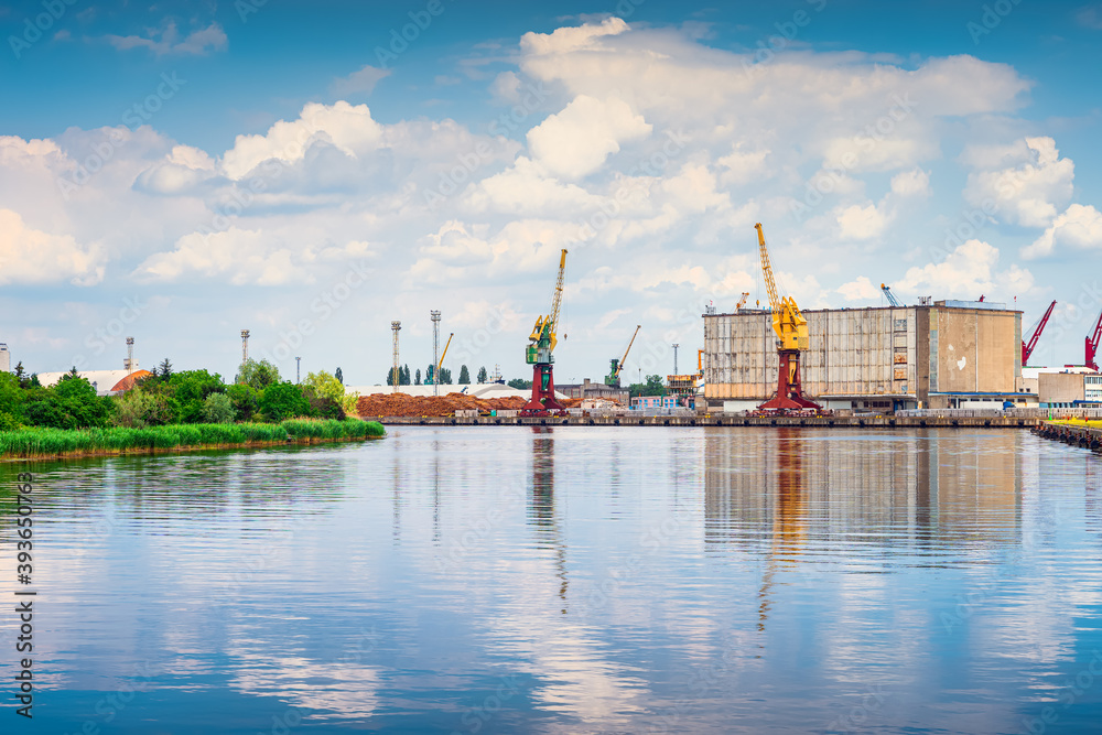 Cargo, industrial port and harbour in Szczecin with stacks of timer, tall dock cranes and industrial machinery. West Pomeranian, Poland