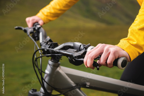 Close-up of woman cyclist hand on handlebars of mtb bike outdoors in mountains