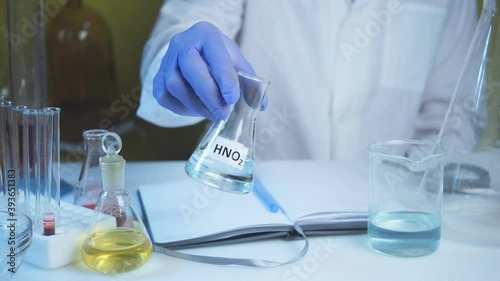 Chemical laboratory food supply. GMO Genetically modified products in the laboratory. A lab technician in a white coat holds nitric acid in his hand.