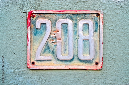 Number 208, two hundred and eight,  a vintage plate on a blue wall. photo