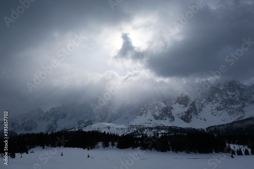 Dramatic winter view of Croda Rossa Di Sesto mountain from area around Alpe di Nemes refuge in Sexten Dolomites, South Tyrol, Italy. Stormy dramatic clouds and sun rays on sky. © Iwona