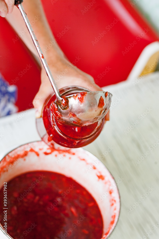 pour fresh strawberry jam into a jar with steel ladle pour fresh strawberry jam into a jar with steel ladle
