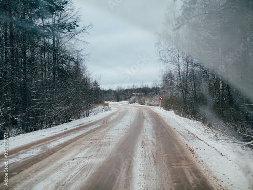 snowy road surrounded by pine trees, driving in winter snow on a country road, selective focus and motion effect © artemidovna