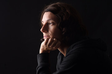 Profile portrait of serious woman with hand on chin and thinking on black background
