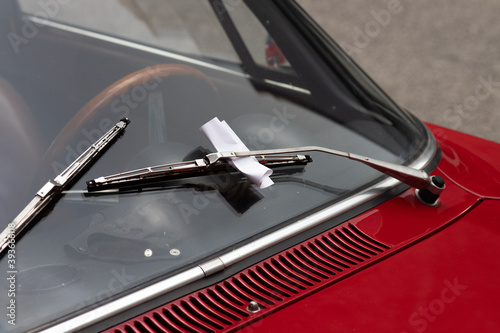 Closeup of a parking violation ticket behind a windshield wiper on a classic car photo