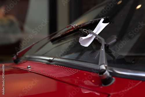 Closeup of a parking violation ticket behind a windshield wiper on a classic car