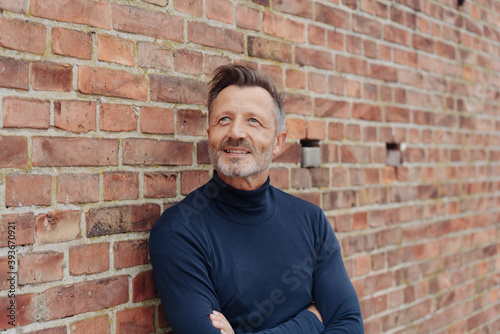Man relaxing against a brick wall looking up
