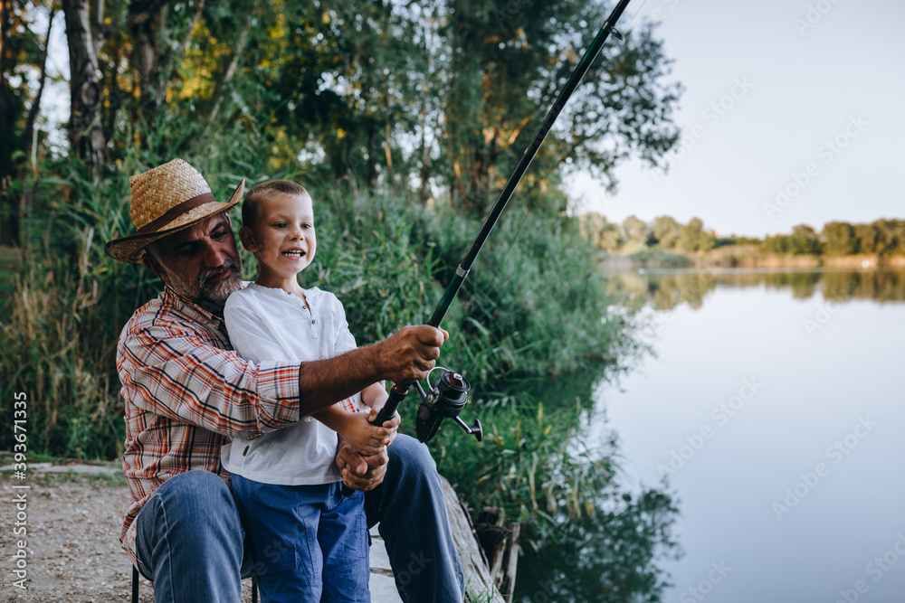 boy fishing on the lake with his grandfather boy fishing on the lake with his grandfather