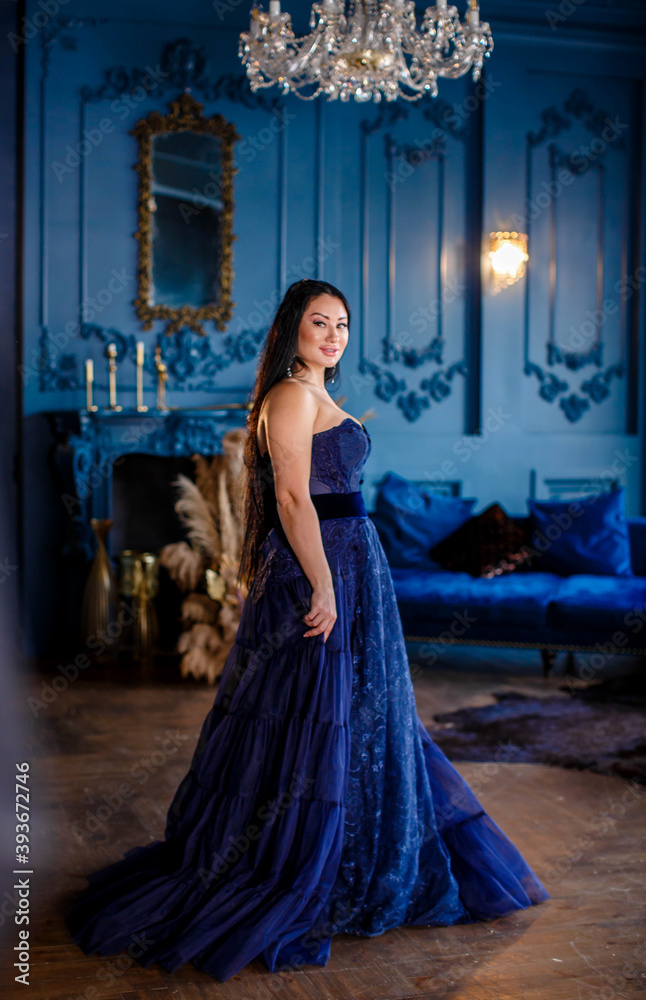 Beautiful woman in a blue ball gown and blue room