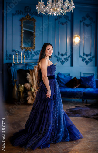 Beautiful woman in a blue ball gown and blue room © popovatetiana