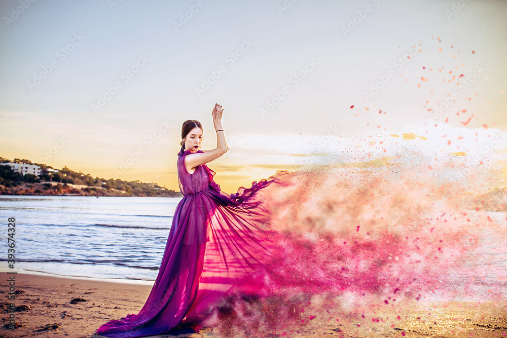 Woman in purple Flying Dress with disperse dust effect Fluttering on Wind, Girl in Waving Gown on Sundown Sea Woman in purple Flying Dress with disperse dust effect Fluttering on Wind, Girl in Waving Gown on Sundown Sea
