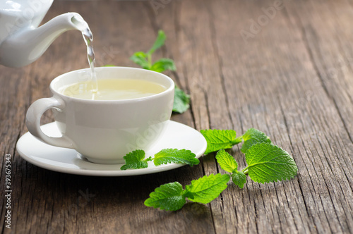 White cup of melissa herbal tea with fresh melissa leaf, organic aromatherapy relaxation hot drink concept, Melissa officinalis