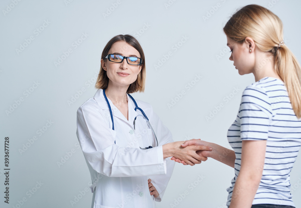 Woman doctor and patient shaking hands on a light background communicating medicine Woman doctor and patient shaking hands on a light background communicating medicine