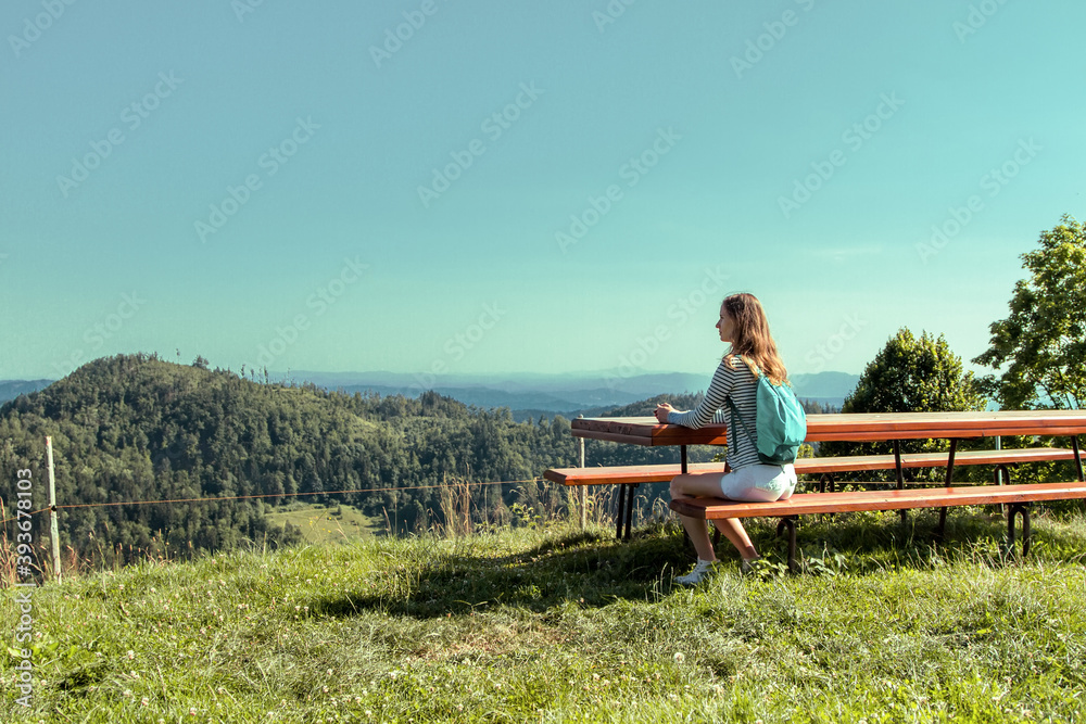Woman tourist sitting on a bench on a hill and looking at the landscape at nature.