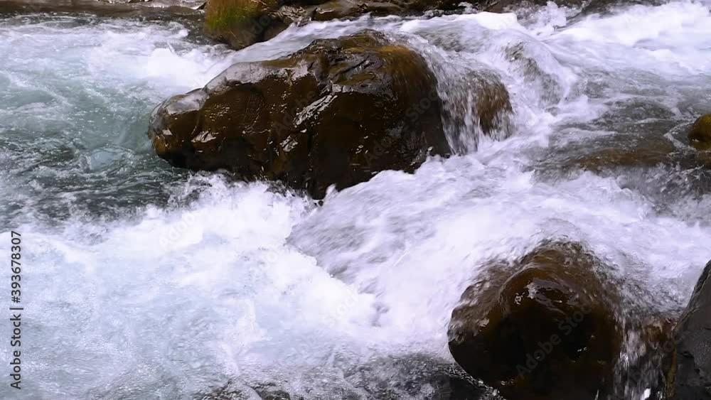 Wild mountain river flowing with stone boulders and stone rapids. Pure mountain water flows over rocks covered Wild mountain river flowing with stone boulders and stone rapids. Pure mountain water flows over rocks covered