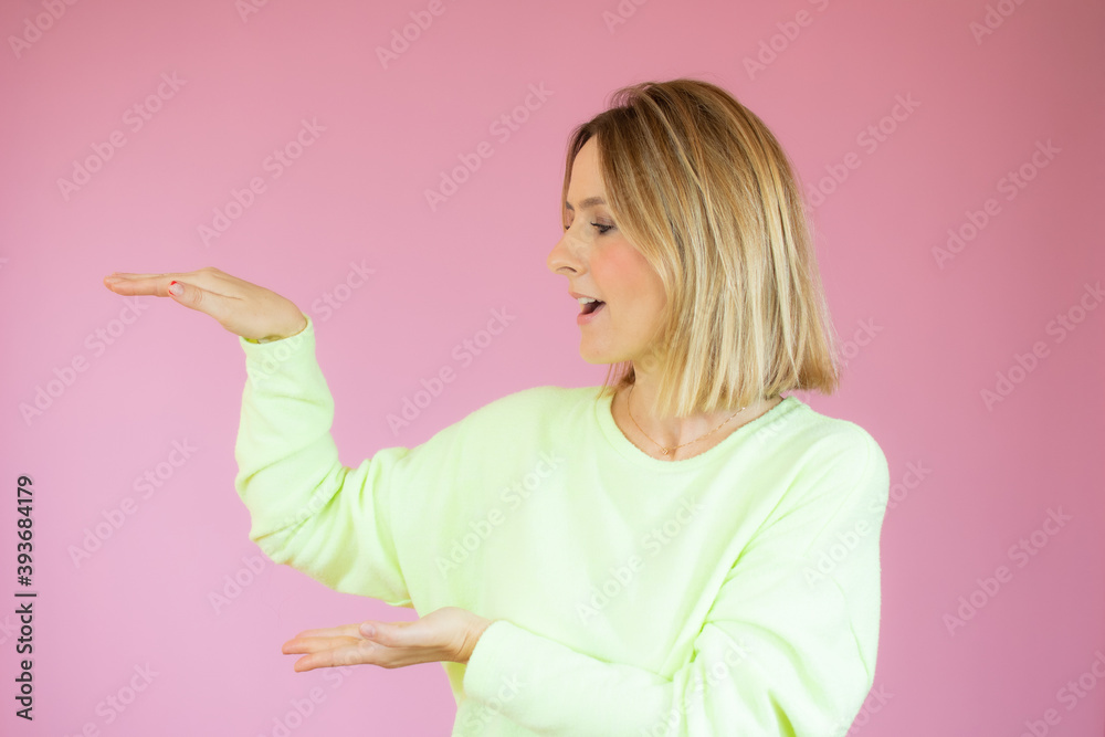 Happy Young Woman in casual sweater Presenting On pink Background Happy Young Woman in casual sweater Presenting On pink Background