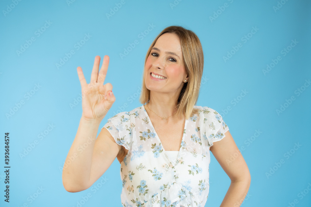 Beautiful blonde woman counting three standing over isolated blue background Beautiful blonde woman counting three standing over isolated blue background