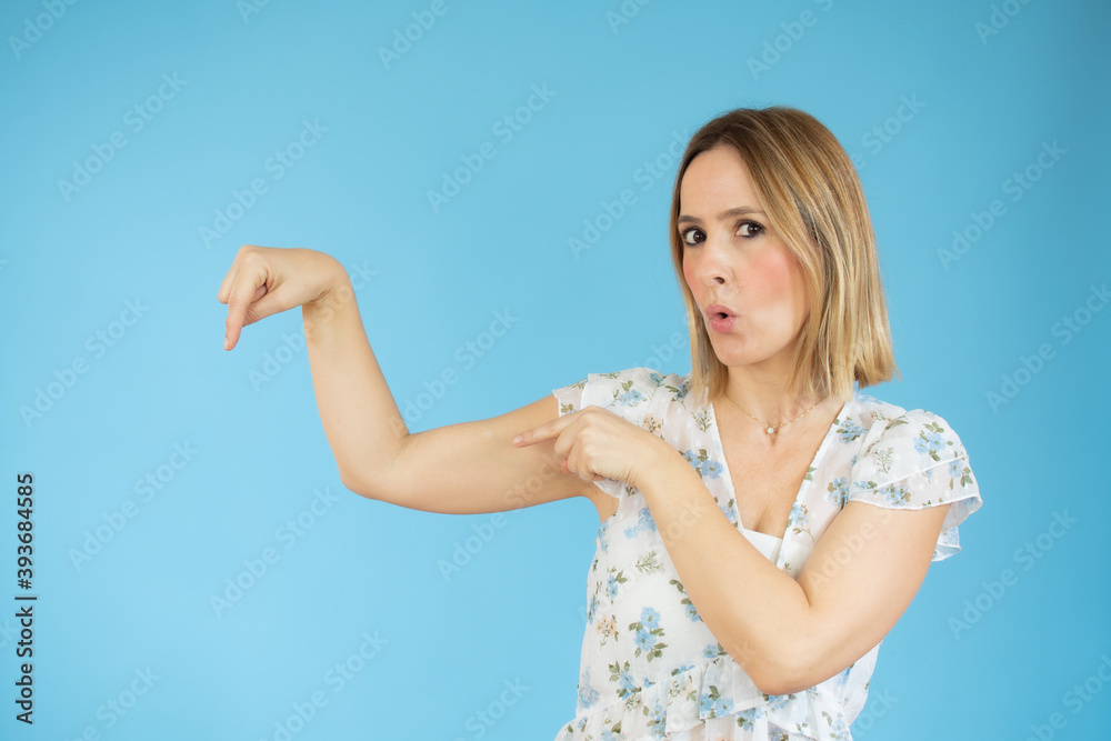 Young woman over isolated blue background pointing fingers to the side Young woman over isolated blue background pointing fingers to the side