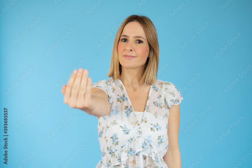 Young woman over isolated blue background inviting to come with hand. Happy that you came Young woman over isolated blue background inviting to come with hand. Happy that you came
