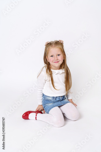 The girl is sitting on the floor. Isolated over white background.