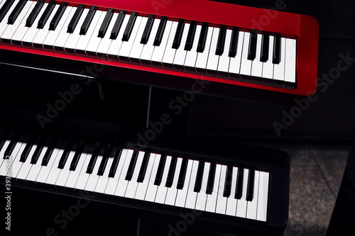 Electronic synthesizers (piano keyboards) close-up shot with dark background. Beautiful red and black musical keyboards with balck and white keys. Modern, minimalistic look, top view.