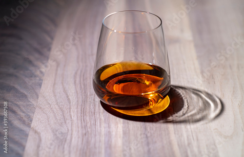 a glass of whiskey on walnut wood texture close-up © Andrey