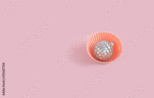 Cupcake with disco ball Christmas tree decoration isolated on pastel pink background. Flat lay design