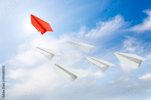 red paper plane leading others