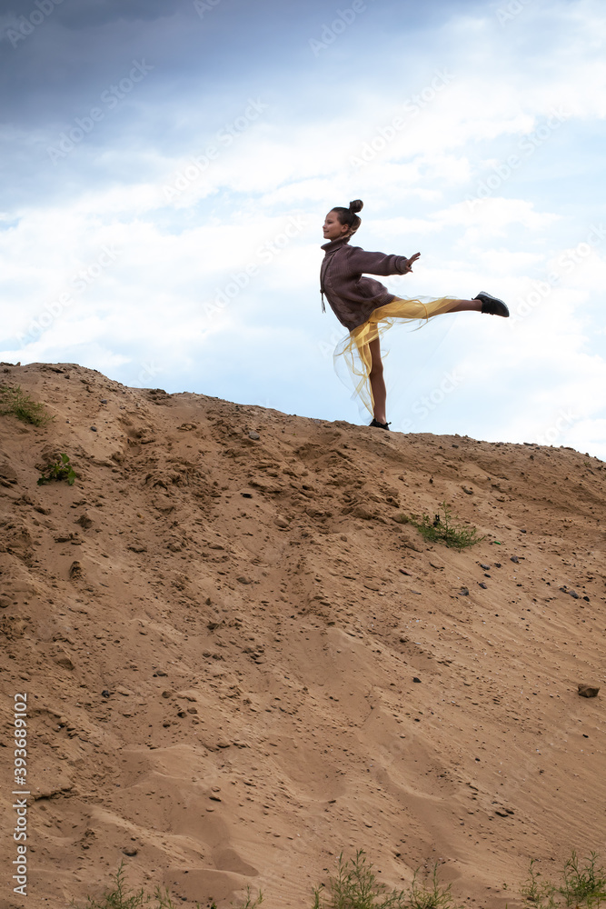Girl doing balance gymnastics exercise on top of sand hill