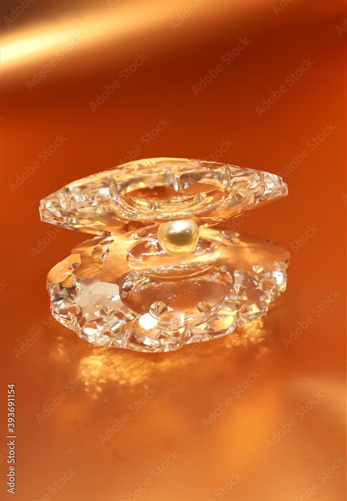 White crystal pearl in a shell show piece isolated on golden orange background with space to write your text