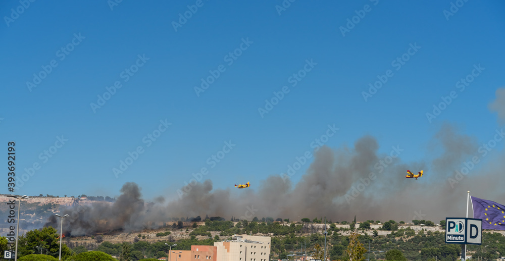 fire starts on the hills of Marseille, near Marignane airport. two yellow fire-fighting planes are going to throwing water on it. 