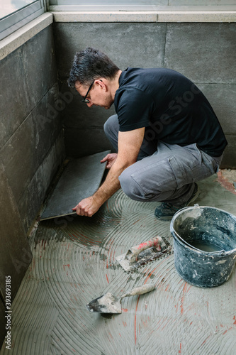 Workman laying a new tile floor on a terrace