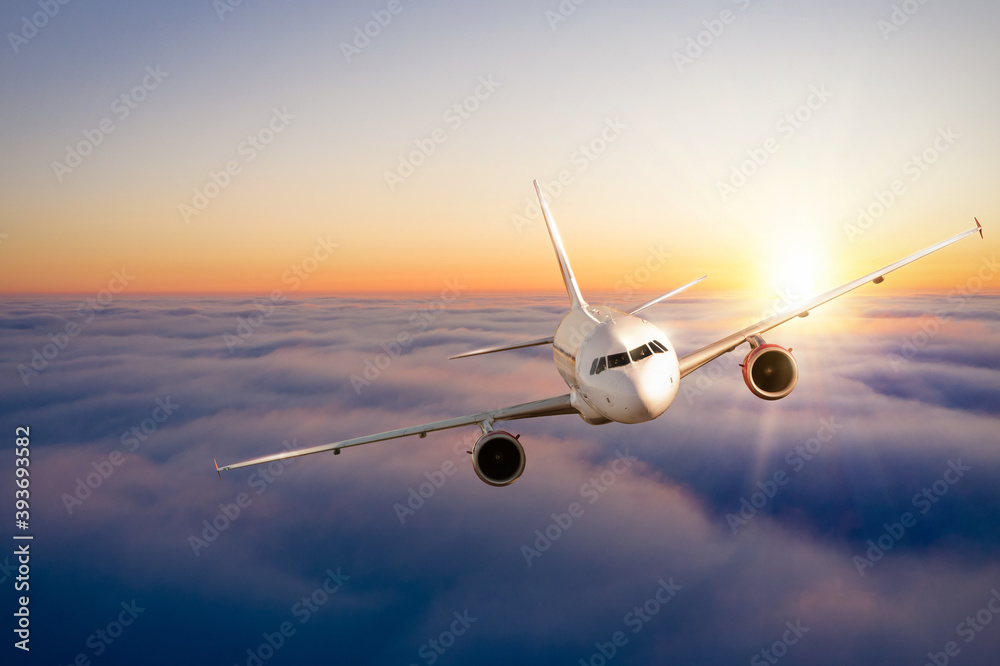 Fototapeta premium Commercial airplane flying above clouds in dramatic sunset light.