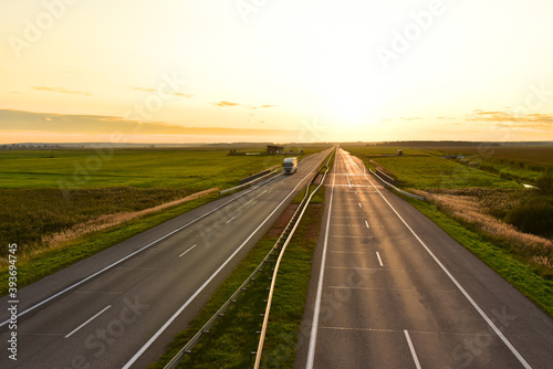 Truck with semi-trailer driving along highway on the sunset background. Out of focus, possible granularity, motion blur © MaxSafaniuk