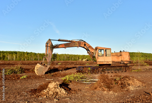 Fotografia Excavator digging drainage ditch in peat extraction site