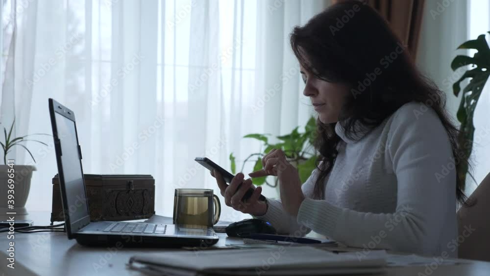 Woman Calculates Expenses on Smartphone Counting Money Dollar Cash while Working Bills Taxes Planning Family Budget. Serious Housewife at Office Table. Evening at Home. 2x Slow motion 60 fps 4K