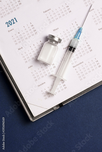 syringe and vaccine with calendar 2021, blue background