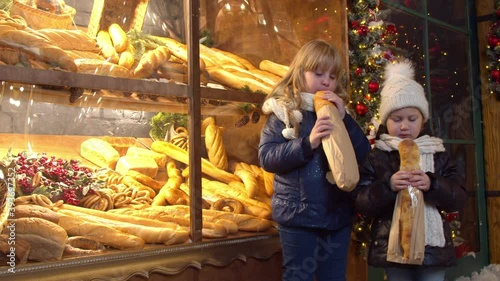 Siblings eating bread near bakery in evening