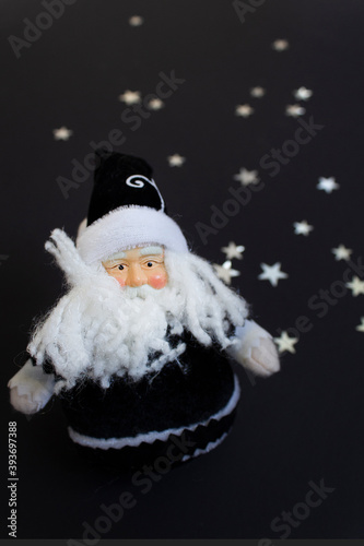 Santa Claus Christmas toy on black background with stars New Year congratulations vertical card 