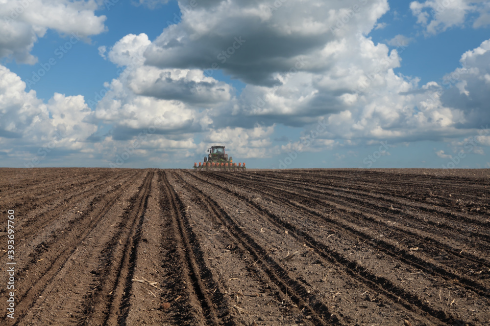 Obraz premium Tractor sowing field in spring, selective focus on land, agricultural works in spring