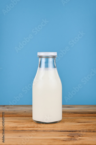 Close up one glass bottle of milk over blue