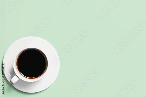 Cup of coffee on a green background. Coffee cup top view.