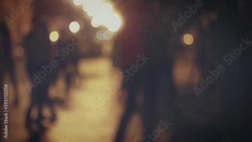Blurred silhouettes of dancing couples in the night street in slow motion.