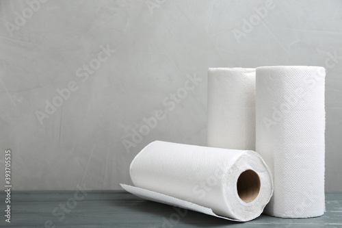 Rolls of paper towels on grey wooden table, space for text