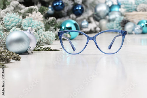 christmas eyeglasses blue spectacles isolated on white table with balls and decorations useful as a greeting gift card template with copy space