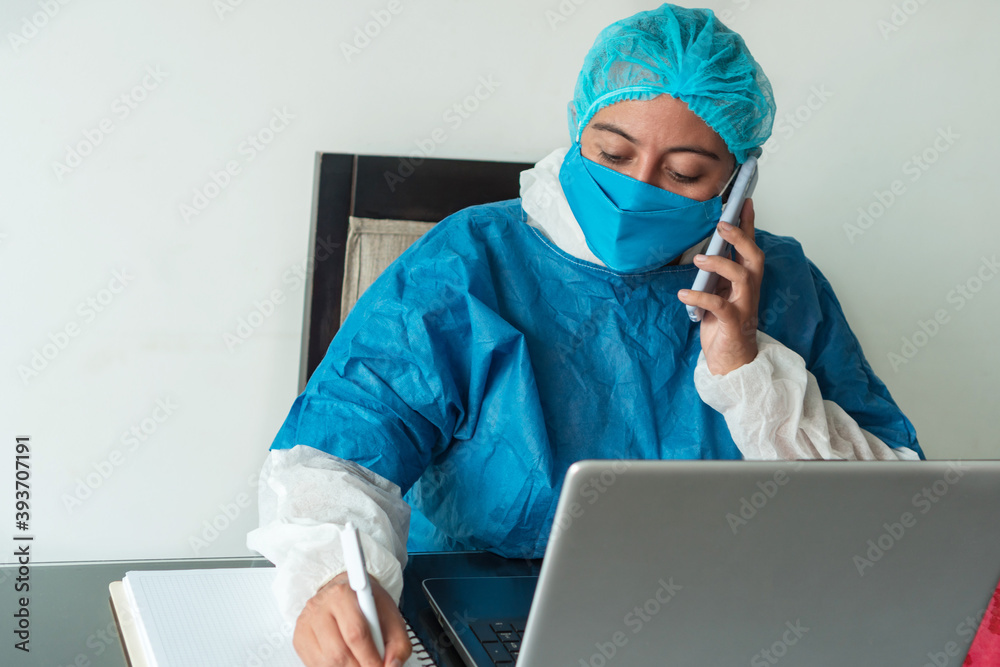 Exhausted doctor with a medical surgical mask on his face and the doctor's uniform talking on his cell phone Exhausted doctor with a medical surgical mask on his face and the doctor's uniform talking on his cell phone